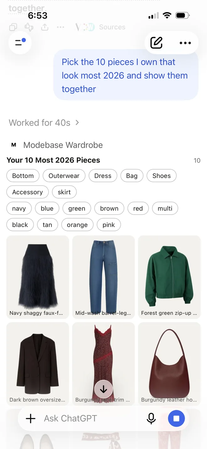 A grid of pieces from the wardrobe picked as most 2026: a navy shaggy faux fur skirt, mid wash barrel leg jeans, a forest green zip up jacket, a dark brown oversized blazer, a burgundy lace trim dress, a burgundy leather bag, charcoal textured ballet flats, a rust printed silk waist scarf and red floral embroidered trousers